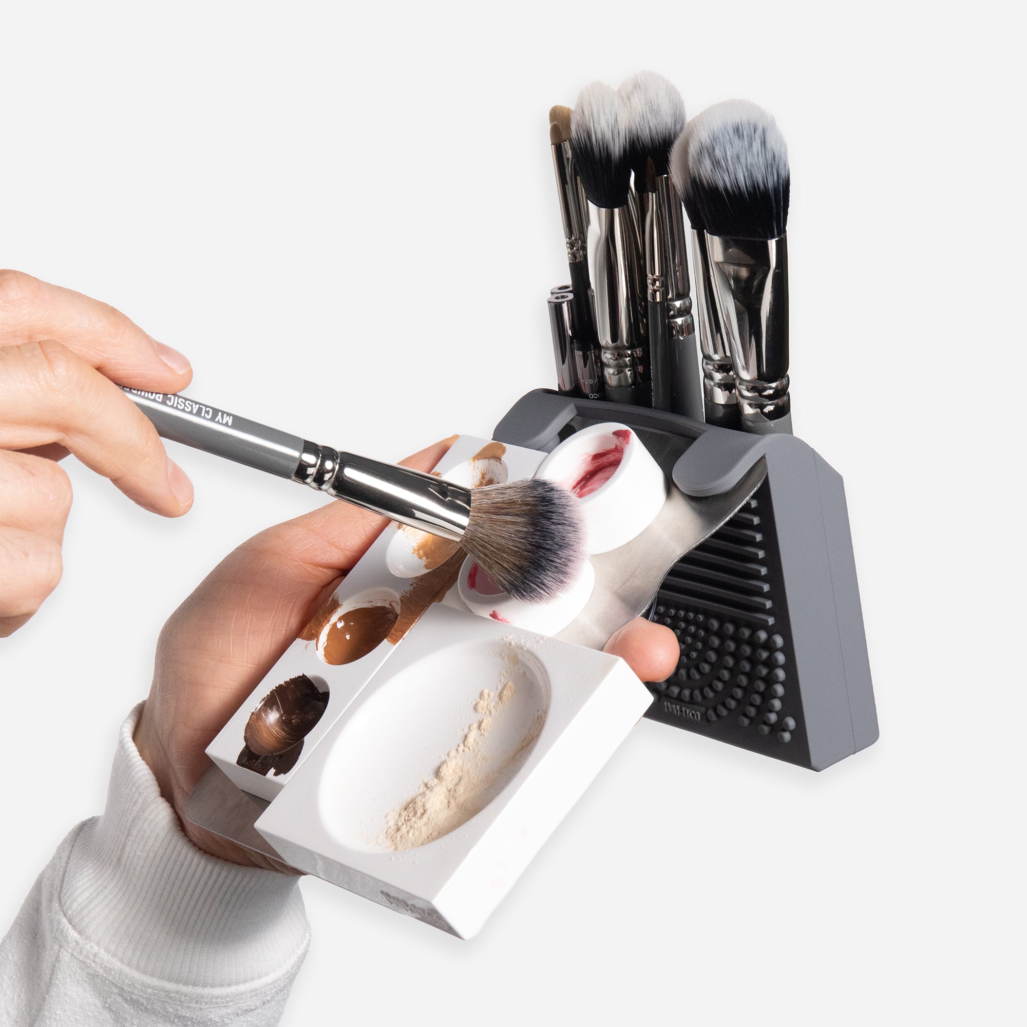 MYNETICS 'On Hand' kit by MYKITCO, featuring a palette with various makeup shades held in hand for easy application.